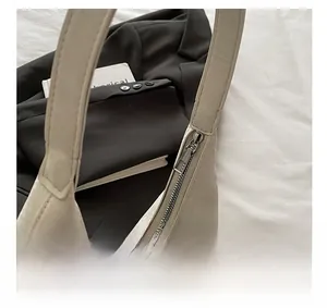 Detailed macro view of the smooth metallic zipper closure on an off-white shoulder bag