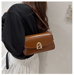 Vue détaillée d'un sac bandoulière en cuir marron avec boucle dorée sur un mannequin