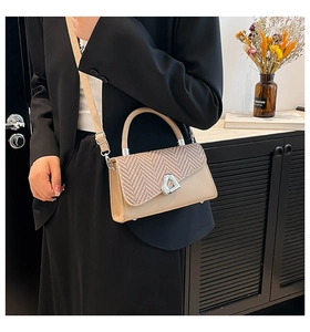 Close-up of beige crossbody bag with herringbone weave and silver heart-shaped clasp