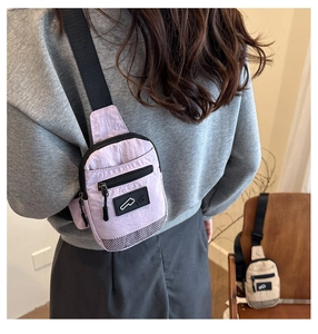 Détail du sac bandoulière en nylon violet clair avec poche zippée noire et décor en maille