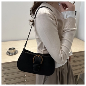Detail of a vintage black leather underarm bag with an elegant golden horseshoe buckle