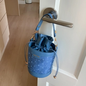 Détail du sac seau bleu en denim et cuir avec quincaillerie dorée et cordon de serrage
