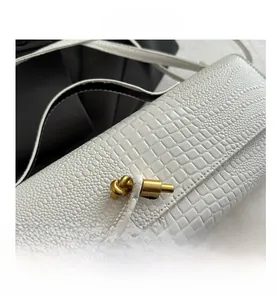 Close-up of white crocodile and lychee leather textures with a gold knot metal buckle