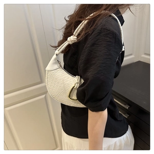 Detail of white moon bag with woven leather texture and golden D-buckle hardware
