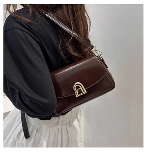 Détail du sac à rabat en cuir PU chocolat avec une boucle dorée en forme de fer à cheval