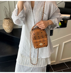 Détail d'un mini sac à dos en cuir marron avec motifs d'ours et chaîne dorée