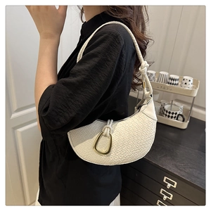 Detail of white woven crescent shoulder bag with golden D-ring buckle and knotted strap