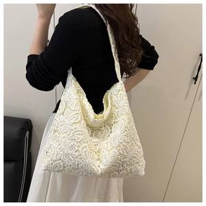 Détail de la broderie florale en dentelle et texture du tissu sur la bandoulière du sac blanc