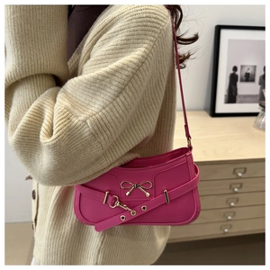 Détail du sac à main fuchsia avec nœud doré et bandoulière en cuir avec œillets