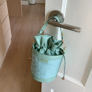 Détail du sac seau vert sauge montrant le patchwork texturé et la fermeture à cordon