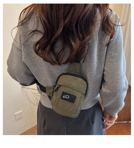 Rear view of a khaki military-style nylon crossbody bag worn across the body