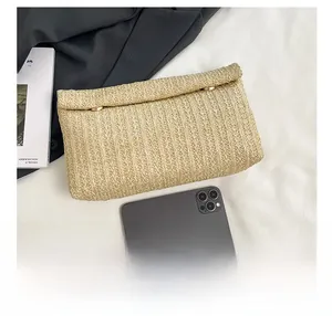 Detailed view of the woven envelope clutch bag compared with a smartphone for size reference