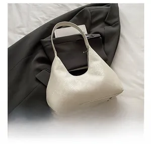 Detail view of cream snake-embossed shoulder bag with a phone for size reference