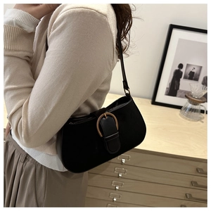 Detail of a black crescent underarm bag with a vintage gold horseshoe buckle on a model