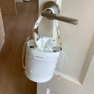 Vue détaillée du sac seau blanc avec fermeture à cordon et détails de texture à points 3D