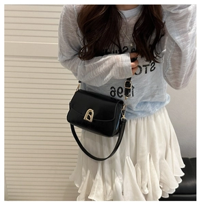 Detail view of black matte leather shoulder bag featuring a U-shaped gold metal lock buckle