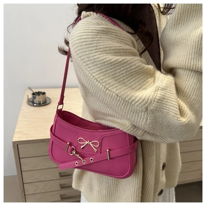 Detail of rose red underarm bag with golden bow ornament and decorative belt buckle