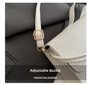 Detail view of white crocodile embossed leather bag with premium gold metal adjustment buckle
