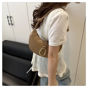 Close-up of retro brown woven shoulder bag with golden buckle and knotted strap