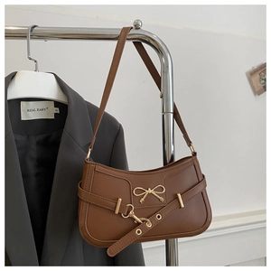 Détail du sac à bandoulière marron foncé avec noeud en métal doré et boucle décorative