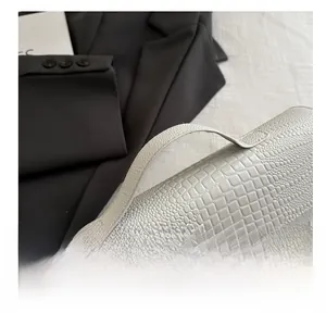 Detail of white snakeskin texture handbag showing handle stitching and metal twist lock