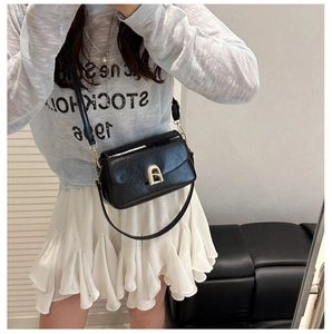Détail d'un sac à main en cuir noir brillant avec une boucle en métal doré