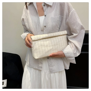 Close-up of white woven clutch bag showing detailed vertical wave texture and flap closure