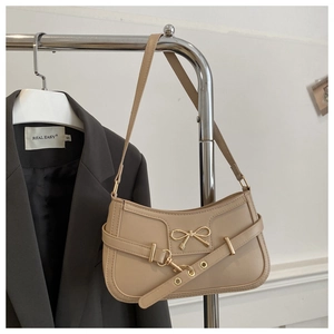 Détail du sac à bandoulière beige avec fermoir papillon doré et ceinture à boucle métal