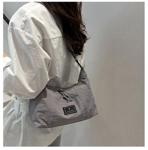 Detail van grijze nylon hobo tas met logo-patch en geknoopte ritstrekkers voor dames