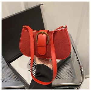 Detail of red vintage underarm bag featuring suede texture and bronze buckle accent