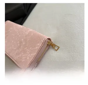 Detail of smooth gold zipper and pink snakeskin texture on a fashion long wallet