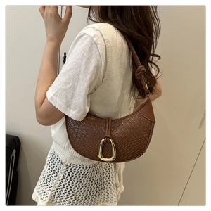 Detailed shot of brown crescent bag with woven texture and gold horseshoe buckle