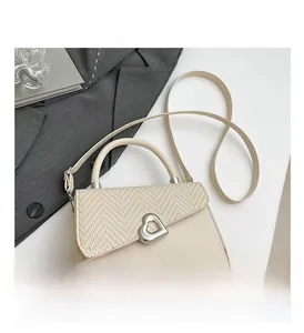 Detail of silver heart buckle on cream leather and herringbone stitched handbag