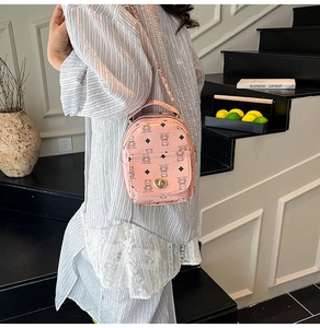 Détail du mini sac à dos rose avec imprimé ours et bandoulière en chaîne sur escalier