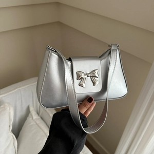 Silver metallic baguette shoulder bag with butterfly buckle shown in casual handheld view