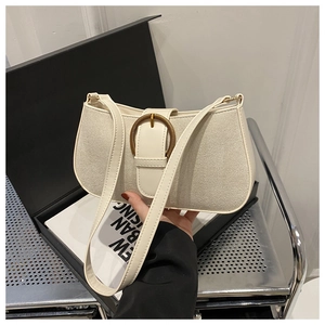Detail of white PU leather underarm bag with large gold buckle and slim shoulder strap