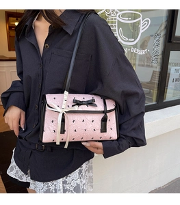 Detail of pink bow shoulder bag featuring rabbit prints and satin ribbon on the strap