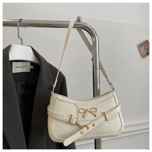 Détail du sac sous l'aisselle en cuir blanc avec nœud doré et sangle décorative