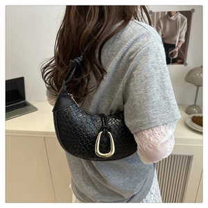 Close-up of woven black hobo bag with a decorative gold horseshoe buckle and knot detail