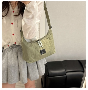 Detail of green nylon crossbody bag showing the adjustable strap and zipper closure