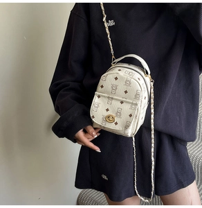 Détail d'un mini sac à dos crème avec motif ours et fermoir rotatif doré élégant