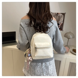 Mini zaino crema con ciondolo a forma di volpe indossato da modella in ufficio chic