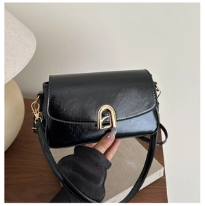 Détail du sac rétro noir montrant le cuir synthétique texturé et la boucle en métal doré
