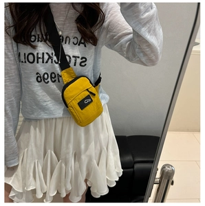 Detail shot of yellow nylon crossbody chest bag with adjustable strap worn by model