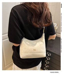 Detailed back view of a white dumpling bag with croc texture and gold hardware on model