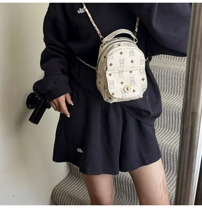 Détail du mini sac à dos en cuir à motif ours, bandoulière chaîne dorée et fermoir pivotant