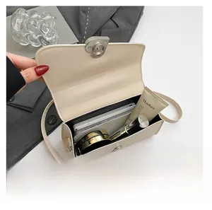 Detail view showing interior capacity of cream crossbody bag with phone and makeup