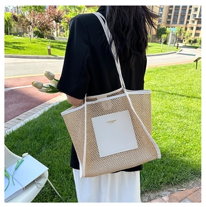 Close-up of beige woven tote bag with white leather trim and gold fashion lettering