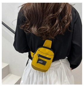 Détail d'un mini sac bandoulière jaune en nylon avec fermeture éclair et empiècement mesh