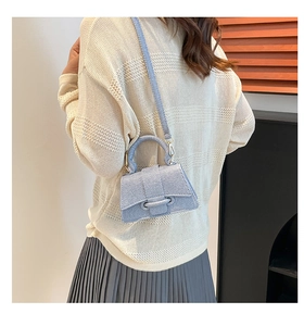 Détail du mini sac sablier en denim bleu clair porté par un mannequin en tenue décontractée